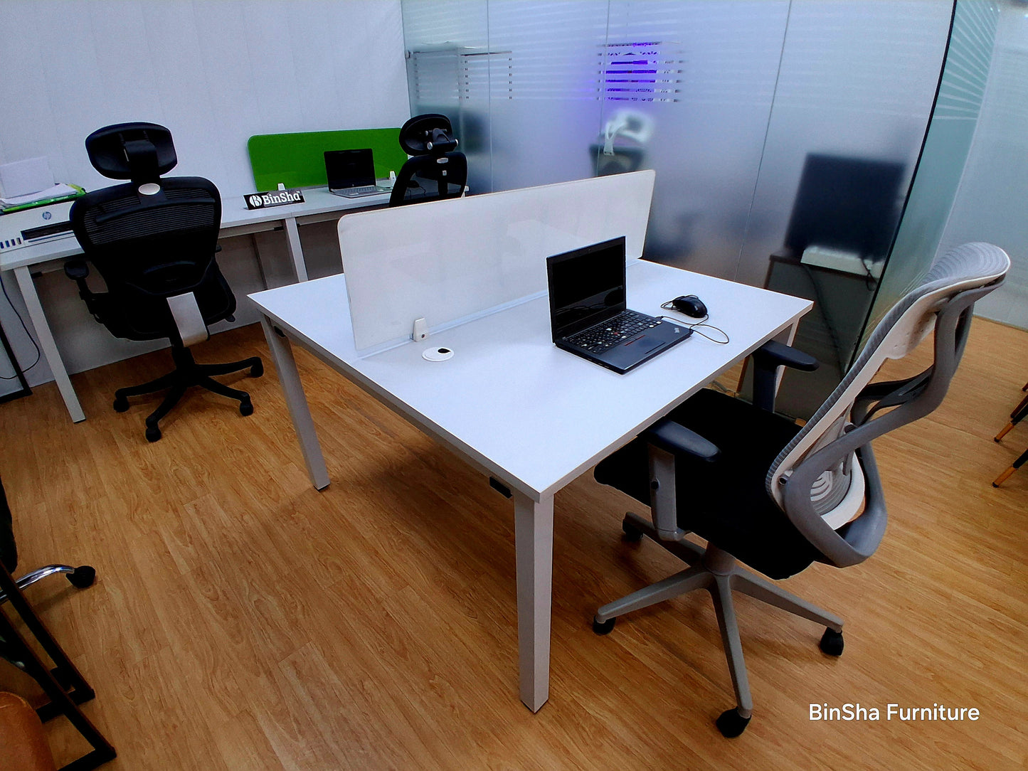 Dual office workstation featuring a wide tabletop, privacy divider panel, and ergonomic chair designed for comfortable long working hours