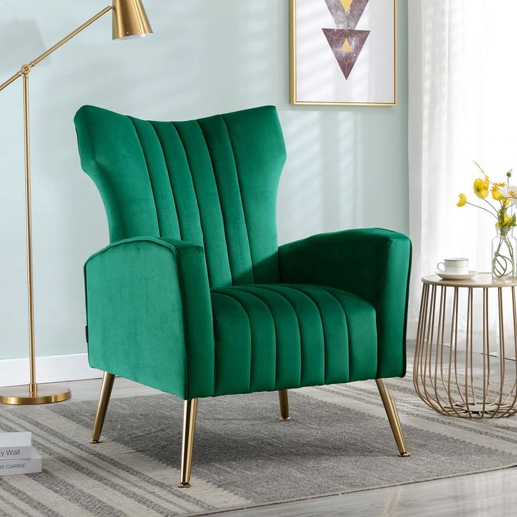 Emerald green velvet wingback accent chair with gold legs in a stylish living room.