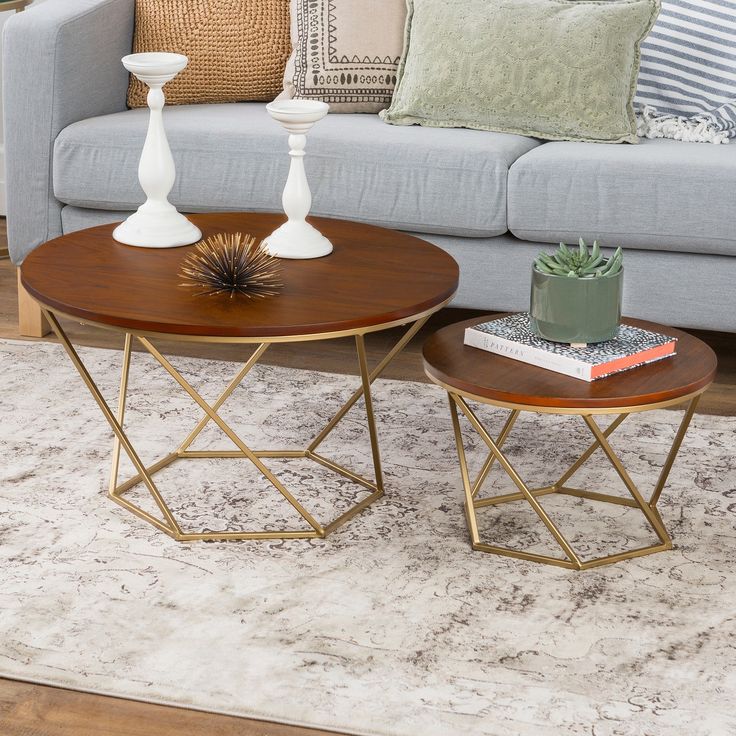 A modern wooden top coffee table set with a gold metal base, placed in front of a grey sofa in a beautifully styled living room