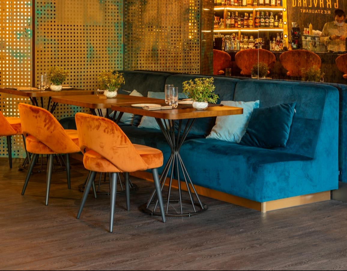 Elegant restaurant interior with stylish velvet seating, warm lighting, and a modern dining setup, creating a cozy and luxurious ambiance