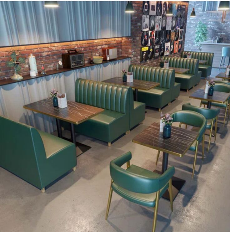 Green retro diner booth seating in a stylish café interior with brick wall and wooden table.