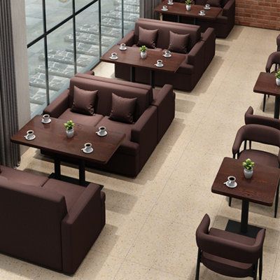 Overhead view of a coffee shop with brown sofa seating and dark wooden tables by large windows