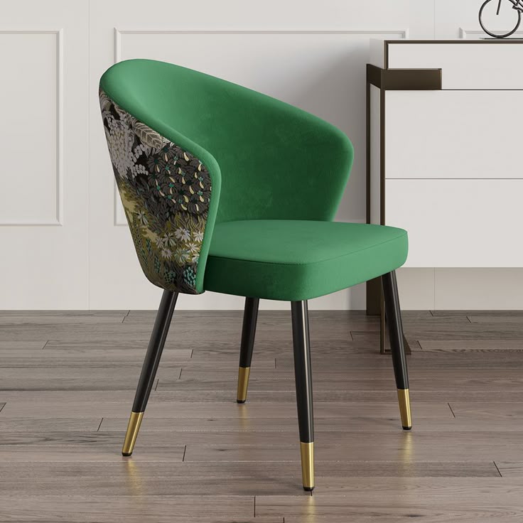 A luxurious green upholstered restaurant chair with a floral-patterned back, black legs with gold tips, placed on a wooden floor in a modern setting.