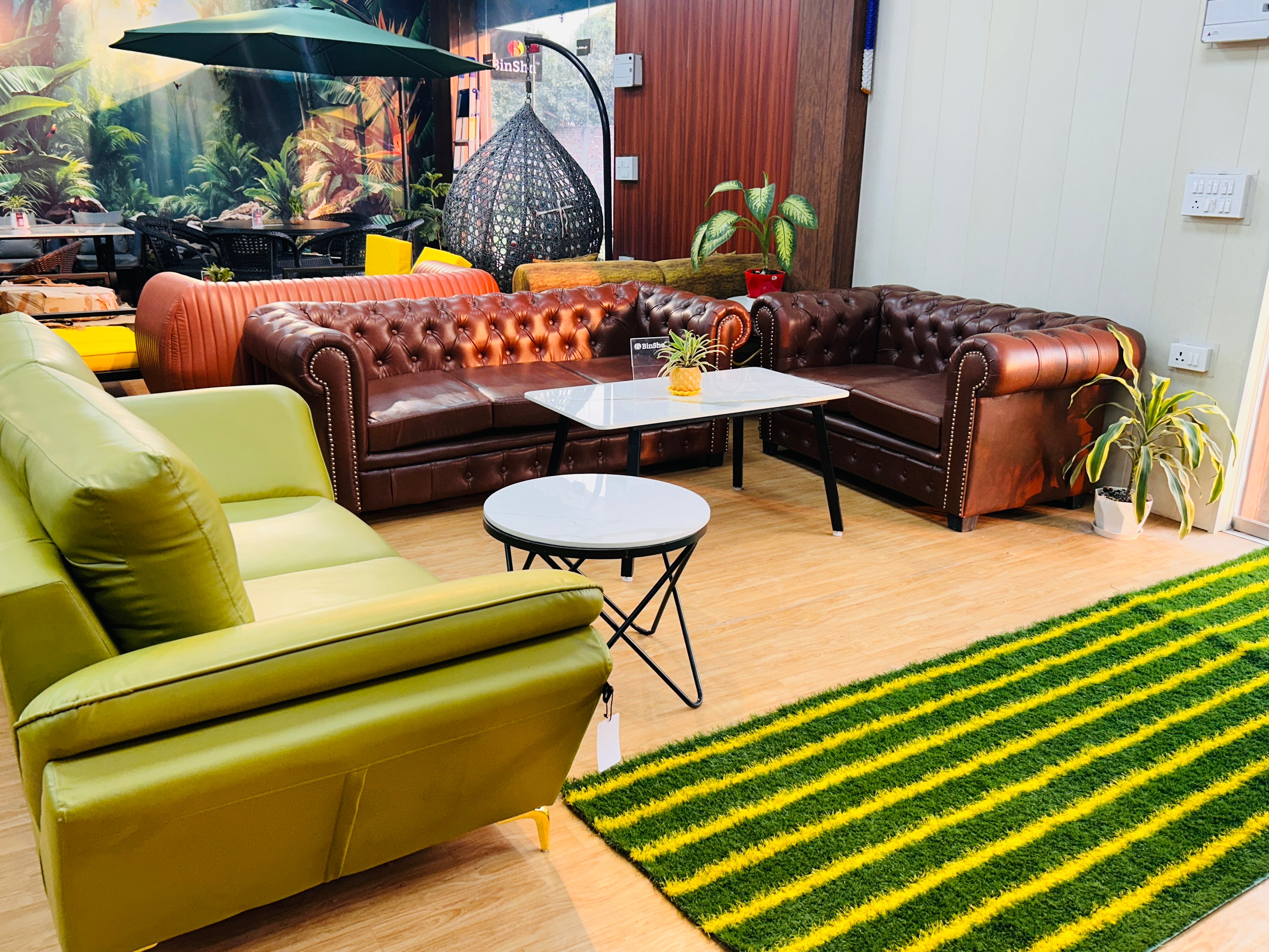 Living room with green sofa, brown leather couches, and a striped green and yellow rug.