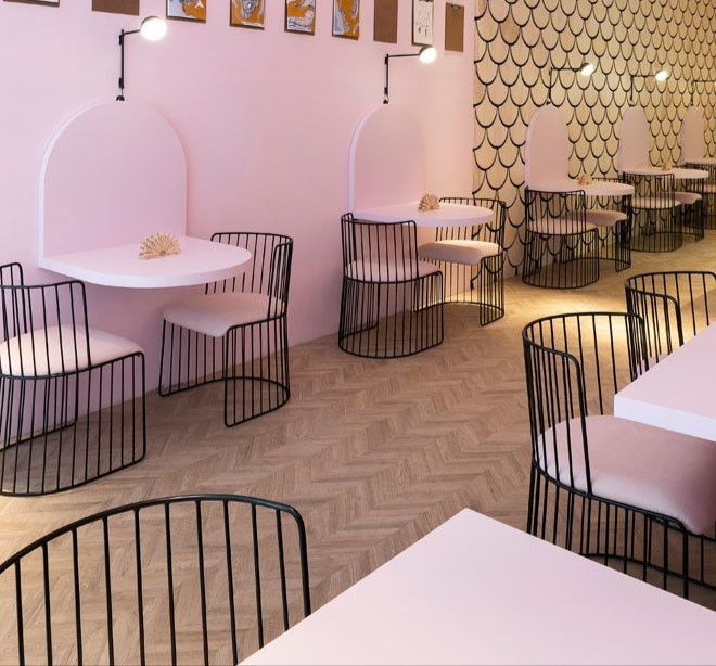Urban café with charcoal walls, orange corner seating, bold floral wall art, and geometric patterned tiles at the bar area.